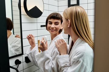 A young woman in a bath robe stands before a mirror, methodically flossing her teeth in a hotel bathroom.