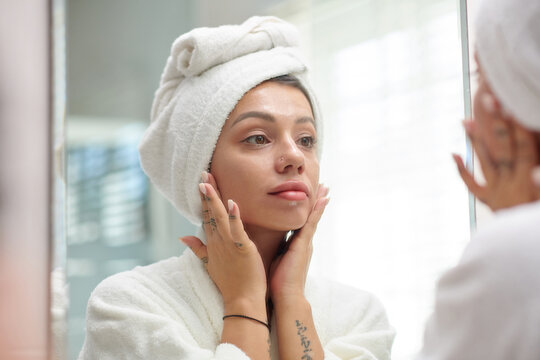Young woman applying face cream after morning shower