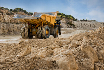 Big yellow quarry truck in a stone through mounds of stones © pavlobaliukh