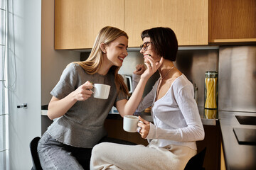 A young lesbian couple enjoying coffee together in a hotel kitchen.