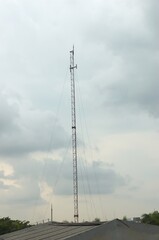 Radio transmitting antenna on top of building with cloudy blue sky in summer weather.