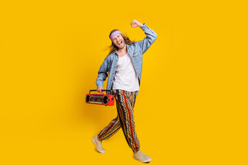 Full body profile portrait of cool young man raise fist walk empty space boombox wear denim shirt isolated on yellow color background