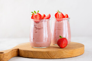 Vegan homemade tofu soy strawberry dessert in a glass on a wooden board. Vertical orientation.