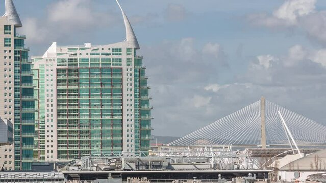 The Parque das Nacoes (Park of Nations) modern neighborhood with skyscrapers aerial timelapse in Lisbon. Vasco da Gama bridge on a background. Clouds passing by. Portugal