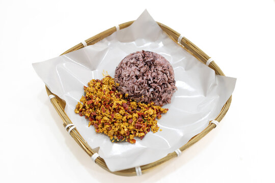 Authentic Southern Thai dry minced pork curry (Kua Kling) served with healthy brown rice in a traditional bamboo basket, isolated on a white background.
