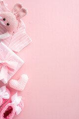 Flat lay vertical of pink baby girl clothes, toys, and gifts on a pastel background, perfect for gender reveal or baby shower