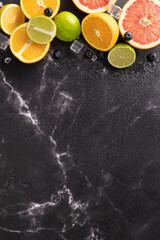 Top vertical view of fresh citrus fruits including oranges, limes, and grapefruits on a dark marble...