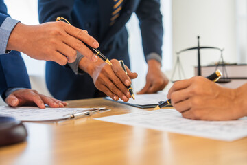 A team meeting of business people and a lawyer in formal suits is taking place at a desk,...