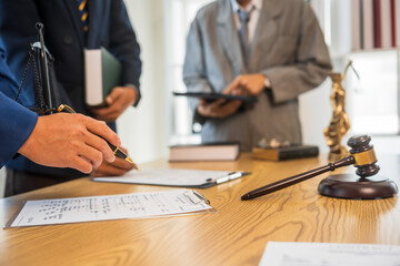 A team meeting of business people and a lawyer in formal suits is taking place at a desk,...