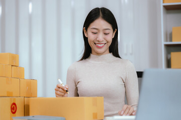 Startup SME small business entrepreneur, young Asian woman, freelancer working at home office, box, smartphone, laptop, online, marketing, packaging, shipping, b2b, SME, ecommerce concept ..