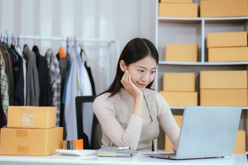 Startup SME small business entrepreneur, young Asian woman, freelancer working at home office, box, smartphone, laptop, online, marketing, packaging, shipping, b2b, SME, ecommerce concept ..