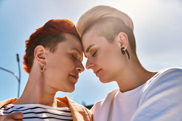 A young lesbian couple proudly stands side by side outdoors, symbolizing love and pride.