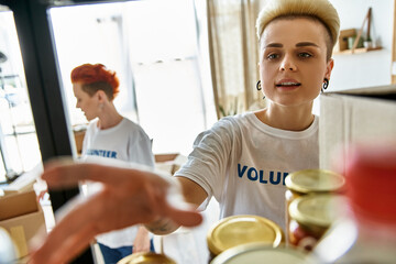 A young woman in a t-shirt in a kitchen setting, part of a lesbian couple volunteering together.