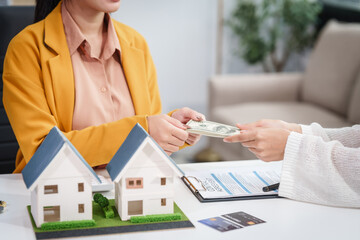 Asian businesswoman discusses home purchase contracts with clients at her desk, focusing on loans,...