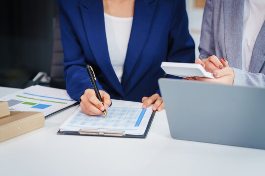Two Asian businesswomen collaborate on stock market strategies and financial services, exchanging comments and suggestions on loan applications and investment opportunities.