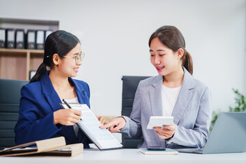 Obraz premium Two Asian businesswomen collaborate on stock market strategies and financial services, exchanging comments and suggestions on loan applications and investment opportunities.