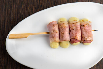 Four pieces of bacon wrapped mochi on a white plate