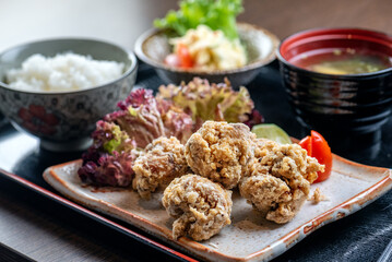 A plate of fried chicken with rice, salad, and miso soup.