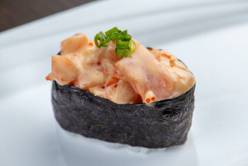 A sushi roll topped with spicy crab salad.