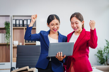 Two successful Asian businesswomen collaborate, discussing comments and suggestions on various...