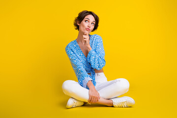 Full length photo of minded girl dressed print blouse sit on floor look at promo empty space think...