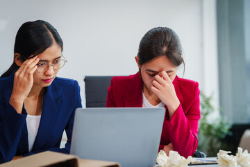 Obraz premium Two Asian businesswomen under stress and pressure discuss financial matters, experiencing anxiety and worry while navigating the complexities of the stock market and loan applications.