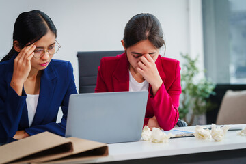 Two Asian businesswomen under stress and pressure discuss financial matters, experiencing anxiety...