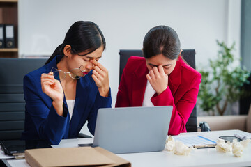 Two Asian businesswomen under stress and pressure discuss financial matters, experiencing anxiety...