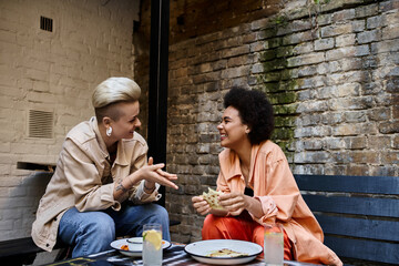 Two diverse women engrossed in a lively conversation at a café table.