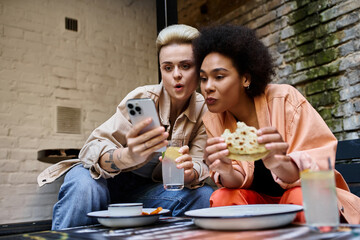 Diverse couple of lesbians sharing a moment with a cell phone in a cozy cafe.