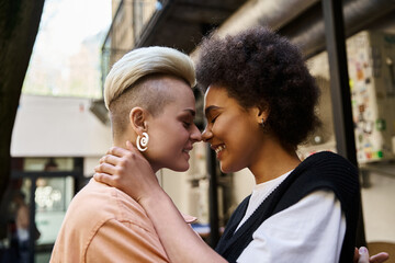 Diverse lesbian couple, stylishly dressed, standing close in a cafe.