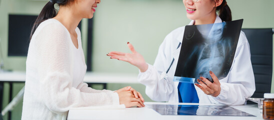 Asian female doctor specializing in psychiatry works at her desk, providing psychotherapy, diagnosis, treatment, and counseling to psychiatric patients, utilizing x-ray films for assessments.