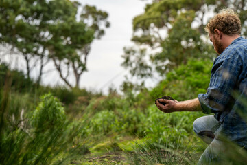 farmer holding soil on her hands on a farm looking after the health of the earth in spring in...