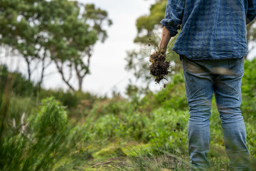 farmer holding soil on her hands on a farm looking after the health of the earth in spring in...