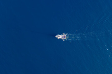 Top down view of a luxury sailboat yacht sailing in open sea with calm blue water