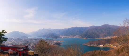 Panorama view of landscape Kawaguchiko lake Japan that can see bridge cross over the lake with blue sky and mountain in background.