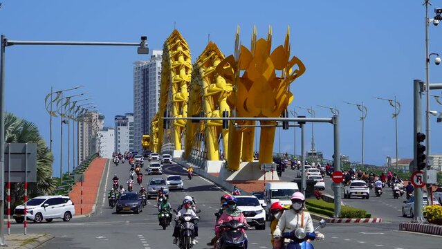 Da Nang, Vietnam - March 9, 2024: Traffic of mopeds and cars driving on the Dragon Bridge 