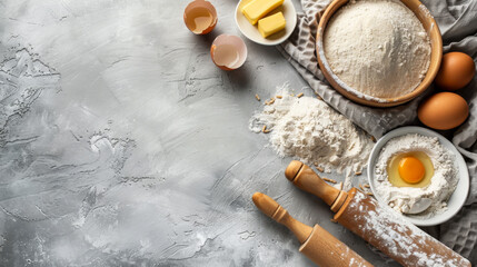 Top view of a gray background with culinary ingredients, flour, eggs, oils and kitchen textiles. Copy space. Baking ingredients. Cooking concept.