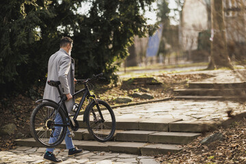 Man Carrying His Bicycle Up Stone Steps in Urban Park