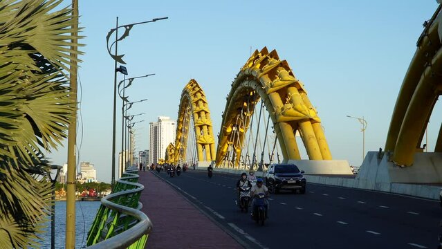 Da Nang, Vietnam - March 9, 2024: Traffic of mopeds and cars driving on the Dragon Bridge during sunset