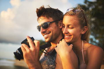 Man, woman and camera at beach for sunset, travel and vacation to island in summer for love. Happy,...