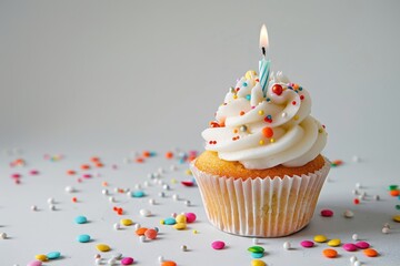 The image includes a birthday cupcake with candle on a light grey table against blurry lights.