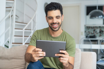 Latin american man with fashionable beard streaming movie on tablet computer