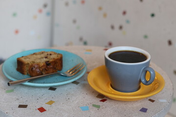 cup of coffee or tea and dessert in coffee shop or restaurant. Drink fragrant black drink during break. modern coffee shop, fresh roasting of coffee beans. grey mug and yellow saucer, colored dishes