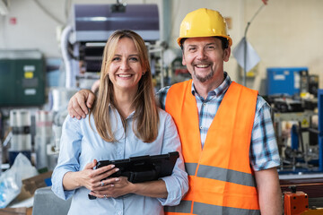 The portrait of supervisor and factory worker stands confidently on the factory line.