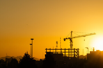 Industrial background with silhouette of construction crane at sunset