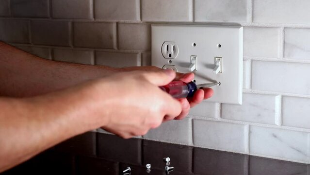 Electrician homeowner removing replacing electrical light outlet cover plate in DIY project