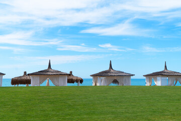 White beach canopies at sunset. Luxury beach tents at luxurious beach resort. Summer beach concept....