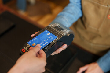 BaristaBusiness Girl Wearing dark blue shirt, wearing brown apron, held  credit card machine. Let...