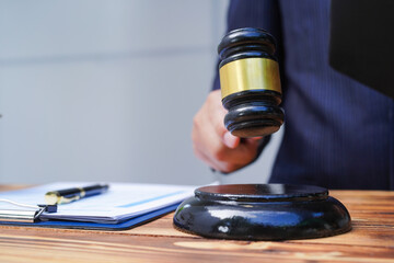 Hands of Asian and African male lawyers working with contract documents and wooden gavel on table in courtroom. Court judges and lawyers
